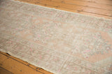 Distressed vintage Oushak runner showing mostly even wear, pale peach, ivory, and pink floral details.