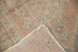 Worn pile of a distressed Oushak rug corner, revealing pink accents and woven reverse.