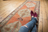 Distressed Oushak rug runner with ivory medallion, scrolling leaves, and abrashed terra cotta field.