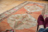 Distressed Oushak runner's sharp leaf medallions with scrolling outlines on abrashed terra cotta.