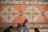 Distressed Oushak runner with terra cotta abrashed field and ivory medallion detail.
