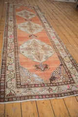 Distressed Oushak rug runner corner with short ivory fringe and worn floral border.