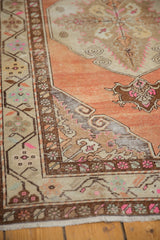 Distressed Oushak runner corner with vibrant terra cotta, beige scrolls, pink details, and worn texture.