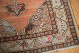 Distressed vintage Oushak runner corner with abrashed terra cotta field, beige border, and pink floral accents.