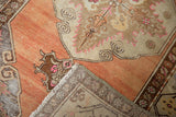 Distressed Oushak rug pile with terra cotta and beige tones, showing wear and hand-knotted backing.