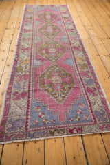 Angled close-up of distressed Oushak runner, softened pink and blue geometric motifs.