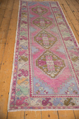 Colorful floral border with aubergine, mint, and yellow blossoms on distressed Oushak runner.