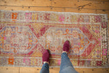 Distressed Turkish Oushak runner with worn pile, vibrant floral motifs, and interconnected medallion.