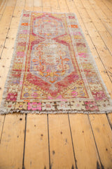 Fringe and distressed pink, yellow, and orange floral designs on the end of a vintage Oushak runner.