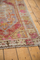 Distressed vintage Oushak runner's end, showing fringe, worn knot heads, and colorful floral motifs.