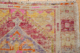 Distressed Oushak runner corner with worn knot heads, fringe, and faded pink, yellow, red motifs.