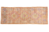 Distressed Vintage Oushak runner with faded peach, lavender, and pale green hook and latch medallions.