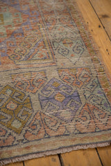 Distressed vintage Oushak rug pile displaying soft mauve, green, and gold motifs.