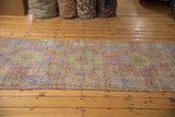 Distressed vintage Turkish Oushak runner, faded mauve, pale green, and gold hook and latch motifs.