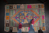 Distressed vintage Oushak square rug with denim blue medallion and colorful serpent spandrels.