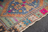 Distressed Oushak rug corner detail, highlighting vibrant geometric patterns and intact side selvage.