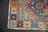 Distressed Vintage Oushak rug corner, worn pile with original selvage and geometric serpent motifs.