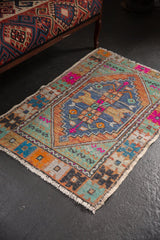 Distressed vintage Oushak rug corner, showing textured wear, fringe, and vibrant geometric patterns.