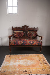 Worn texture and plush pile of distressed Oushak rug, showing gold, sand, and ivory.