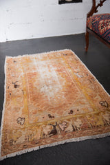 Distressed vintage Oushak rug featuring faded central medallion and sand, gold, ivory hues.