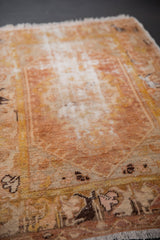 Distressed texture of a vintage hand-knotted Oushak rug with muted gold and sand tones.