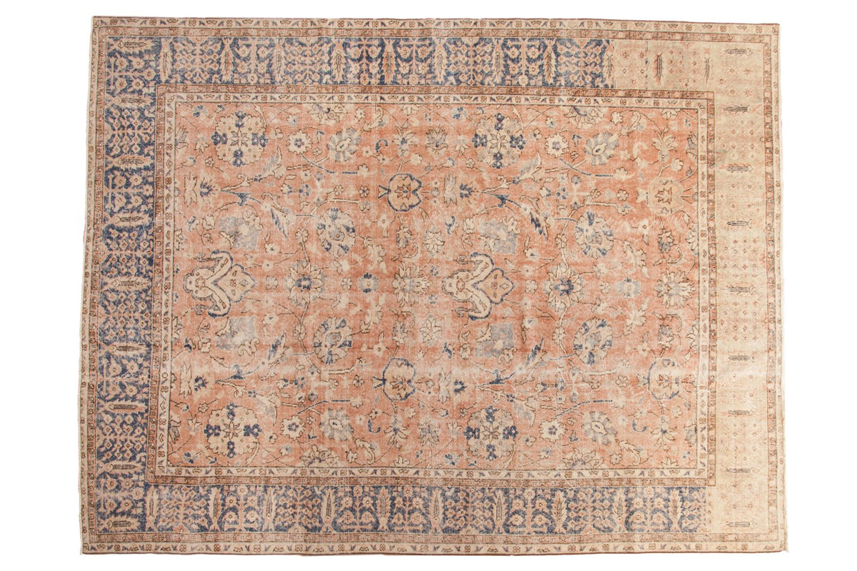Distressed Oushak carpet with allover sprawling floral pattern in muted coral and navy.
