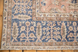 Distressed Oushak corner: navy blue field, beige floral patterns, worn pile, fringe.