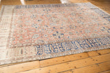 Distressed Oushak carpet corner with faded coral field and navy blue floral border.