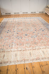 Vintage distressed Oushak rug's ornate beige border contrasting with a faded peach and blue floral field.