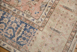 Decorative section of vintage distressed Oushak carpet, showcasing faded navy, beige, and rose floral motifs.