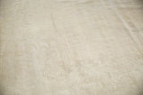 Distressed Oushak rug showing subtle tone-on-tone Rococo pattern and worn neutral pile.