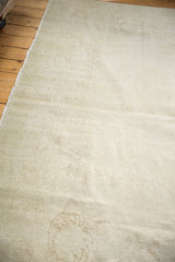Distressed Oushak carpet with worn texture, faint Rococo stylization, and neutral tones.