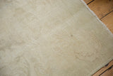 Distressed vintage Oushak carpet pile, neutral tones, faint Rococo pattern, visible foundation wear.