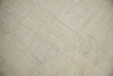 Textured pile of a distressed vintage Oushak rug, showing subtle wear and faint patterns.