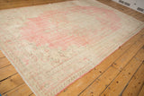 Vintage distressed Oushak carpet displaying soft blush and ivory tones, worn texture, and delicate fringe.