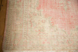 Distressed vintage Oushak carpet corner, faded blush and ivory curvilinear patterns, with fringe.
