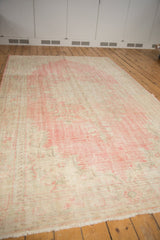 Faded blush pink and ivory distressed Oushak rug texture with floral pattern and fringe.