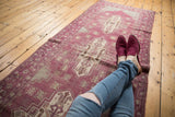 Faded aubergine and ivory stepped medallion with germinating plant motifs on a distressed Oushak runner.