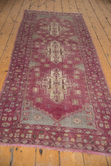Fringe and patterned border of a distressed Oushak runner with aubergine and slate tones.