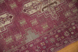 Vintage distressed Oushak rug close-up with aubergine field, stepped geometric patterns, and wear to knot heads.