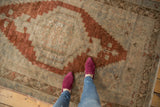 Distressed texture of a vintage Oushak rug with muted rust and ivory geometric medallion.