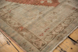 Distressed vintage Oushak rug corner showing faded border motifs and delicate fringe.