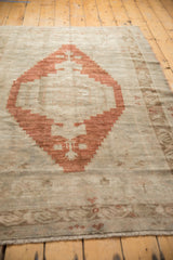 Bottom fringe, distressed texture, and germinating plant motif of a vintage Oushak rug.