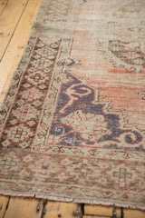 Distressed Oushak carpet detail, showing low pile, visible foundation, dusty rose and dark blue patterns.