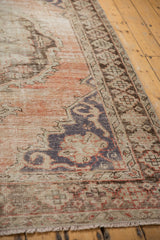 Distressed vintage Oushak rug showing exposed foundation, dusty rose field, and charcoal serrated motifs.