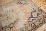 Distressed vintage Oushak rug showcasing faded dusty rose field, dark denim blue motifs, and visible knot heads.