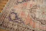 Distressed vintage Oushak rug close-up showing exposed foundation, dusty rose, and pale charcoal.
