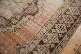 Distressed vintage Oushak rug texture with exposed knot heads, dusty rose, and geometric border.