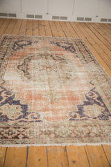 Distressed vintage Oushak rug, central scalloped medallion, dusty rose, denim blue, visible foundation.