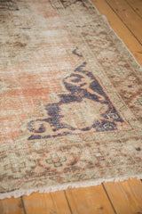 Distressed Oushak rug showing exposed foundation, knot heads, dusty rose-blue pattern, and fringe.